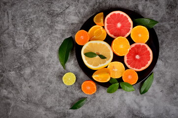 Cut citrus on a plate, Various citrus fruits, Citrus on a concrete background, copy space