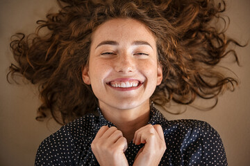 Fototapete - Joyful young woman lying on the floor and laughing