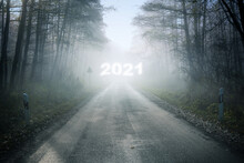 Misty Country Road With A Blurry New Year Number 2021 In The Fog, Leading Through The Forest Into An Uncertain Future, Holiday Concept, Copy Space