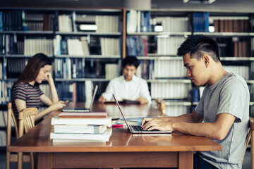 Wall Mural - male asian student studying and reading book in library