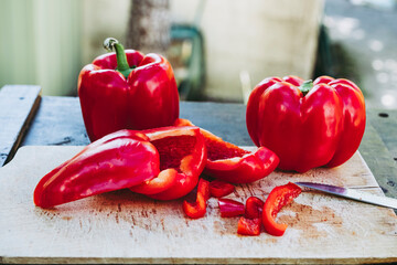 Wall Mural - Préparation en cuisine découpage de poivrons rouges frais sur une planche en bois