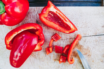 Wall Mural - Préparation en cuisine découpage de poivrons rouges frais sur une planche en bois