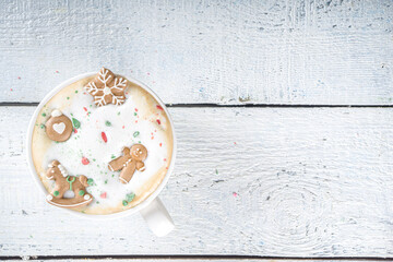 Wall Mural - Coffee Latte or Hot Chocolate Mug with Funny Little Marshmallows in Gingerbread Cookie Forms - Gingerbread man, Snowflake, Christmas Tree Toys. Cute and Cozy Winter Drink Background, cup in Woman Hand