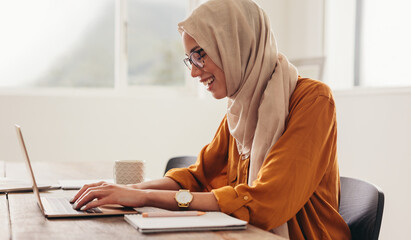 Wall Mural - Businesswoman with hijab writing on the laptop