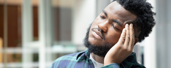 Banner of black African man suffering from headache; sickness concept for vertigo, dizziness, stress, stroke, depression, burnout, Alzheimer disease, brain cancer, memory loss