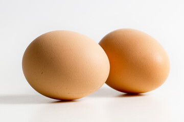 Two brown organic fresh raw eggs. Cut out and isolated on white background with soft shadows for added dimension.