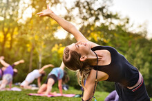 A Group Of Adults Attending A Yoga Class Outside In Park