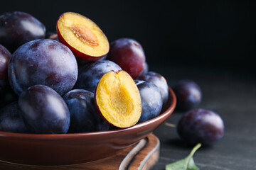 Canvas Print - Delicious ripe plums in bowl on black table, closeup