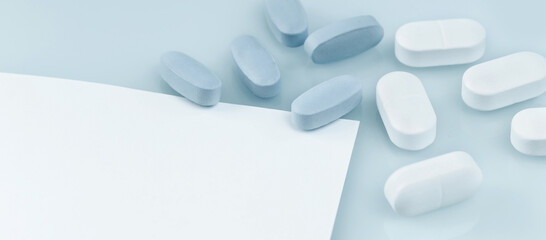 Wall Mural - Medical banner. many white and blue capsule tablets or pills on the table. Close up notice copy space. Healthcare pharmacy and medicine concept. Painkillers or prescription drugs consumption