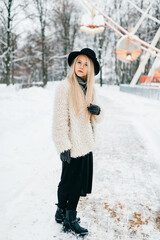 Poster - Stylish beautiful blonde girl in coat and hat posing in the park