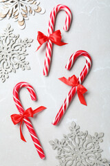 Sweet Christmas candy canes and snowflakes on grey background, flat lay