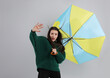 © New Africa - Emotional woman with umbrella caught in gust of wind on grey background