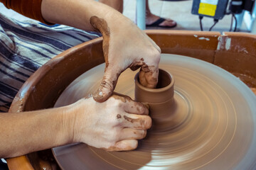 Concept of ceramics, workshop, ceramic art. Close-up on female hands sculpt new utensils with tools and water, female fingers work with pottery and raw clay.