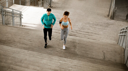 Wall Mural - Young couple running in the urban environment