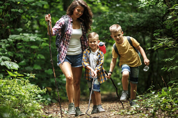 Wall Mural - mother and her little sons hiking trough forest .outdoor spring leisure concept.