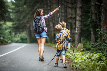 Wall Mural - Mother and her little sons hiking by the rural country road.Outdoor spring leisure concept.	
