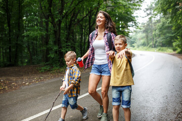 Wall Mural - mother and her little sons hiking by the rural country road.outdoor spring leisure concept.