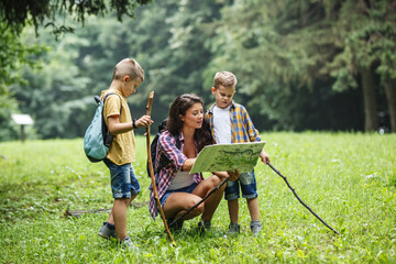 Wall Mural - mother and her little sons hiking . they're taking a break and examining the map.