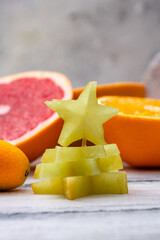 Wall Mural - Sliced carambola assembled like a Christmas tree on tropical fruits background with a candle.