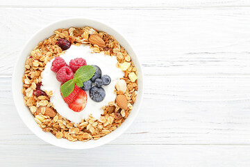 Poster - Tasty granola with fresh berries on white wooden background