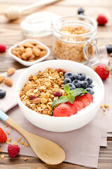 Sticker - Tasty granola with fresh berries and spoon on brown wooden background