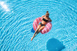 © den-belitsky - Beautiful young woman swimming on the pink donut swim ring in transparent blue water at sunset in summer. Tropical landscape with sexy slim girl in pool, clear water. Top view. Travel. Aerial view