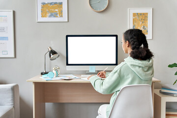 African teen school girl student virtual distance learning online classes looking at mock up white blank empty computer mockup monitor screen remote digital elearning at home. Back over shoulder view