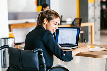 Wall Mural - Young Mexican businesswoman with computer sitting in wheelchair in office in Mexico