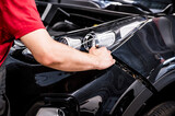 Fototapeta Konie - Close-up of mechanic hands dismantling the bumper of the car