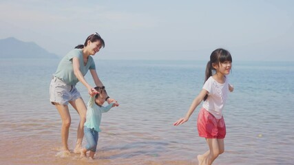 Wall Mural - Asian family playing by stretch the arms, flying like a bird on beach.