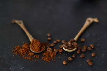 two spoons with coffee on a black background. One spoon with coffee beans. Second spoon with ground coffee. nearby lies coffee bean