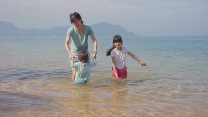 Wall Mural - Asian family feeling relax on vacation, jumping, playing on the beach.