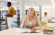 © JackF - Elderly woman makes notes in notebook and read book in public library. High quality photo