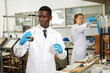 © JackF - Serious male scientists with glass test tubes during chemical experiment , woman on background