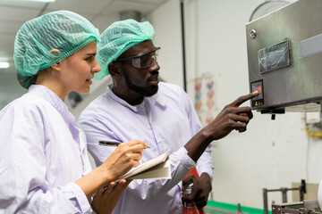 A quality supervisor or food technician explains the use of the Shrink Tunnel Machine to the new employee. Quality inspectors work together in the food factory to inspect food quality in standards.