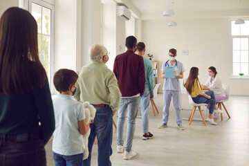 Diverse people lining up waiting for their turn to get shots in modern vaccination center