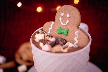 Delicious cup of hot chocolate with a gingerbread man cookie dipped in cinnamon sprinkled chocolates, ideal for a Christmas card.