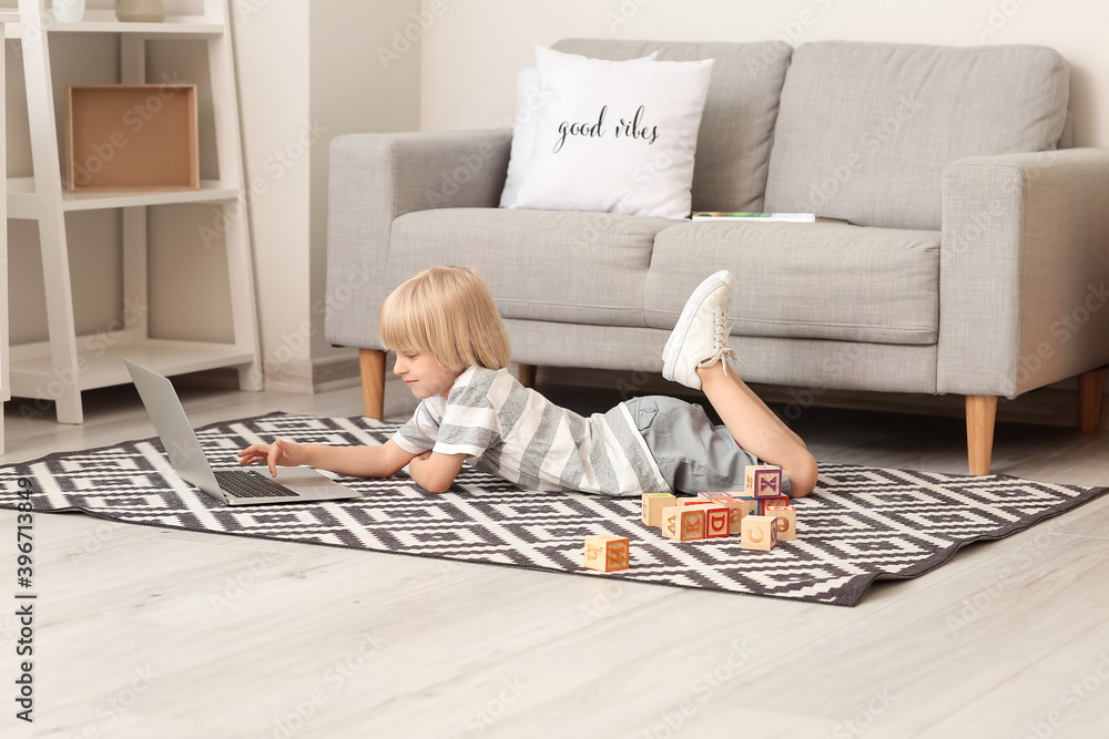 Cute little boy with laptop at home