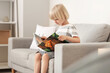 © Pixel-Shot - Cute little boy reading book on sofa at home