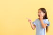© Pixel-Shot - Surprised little girl pointing on something on color background