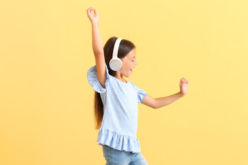 Poster - Cute little girl listing to music and dancing on color background