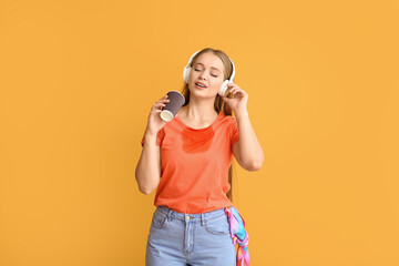 Canvas Print - Young woman with coffee stains on her t-shirt and headphones on color background