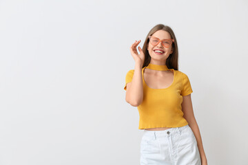 Poster - Happy woman with stylish sunglasses on light background