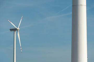 view of a modern windmill against a blue sky. The white blades of the wind turbine close up. Renewable energy source. Production of cheap and safe electricity.