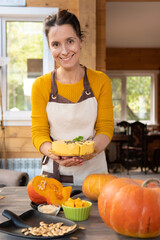 A woman in the kitchen is preparing a pumpkin on the table.