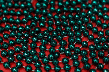 Decorative Christmas Green Beads For Christmas Tree Close Up On Red Background. Beautiful Green Beads. Festive Decoration. Macro Bokeh Beads Abstract Design Background