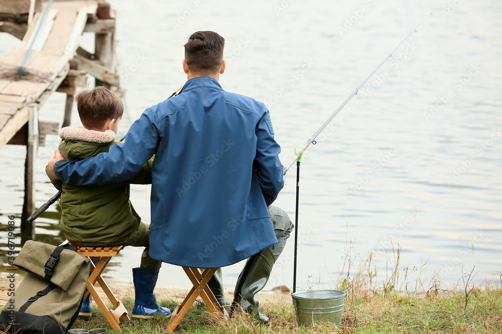 Little boy and his father fishing on river