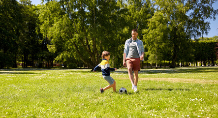 Wall Mural - family, fatherhood and people concept - happy father and little son with ball playing soccer at summer park