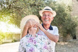 © alex.pin - marito e moglie anziani con il cappello  si divertono in un contesto naturale: Lui chiude gli occhi a lei divertito.