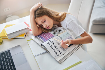 Wall Mural - Sleepy teenager laying her head down while reading grammar rules